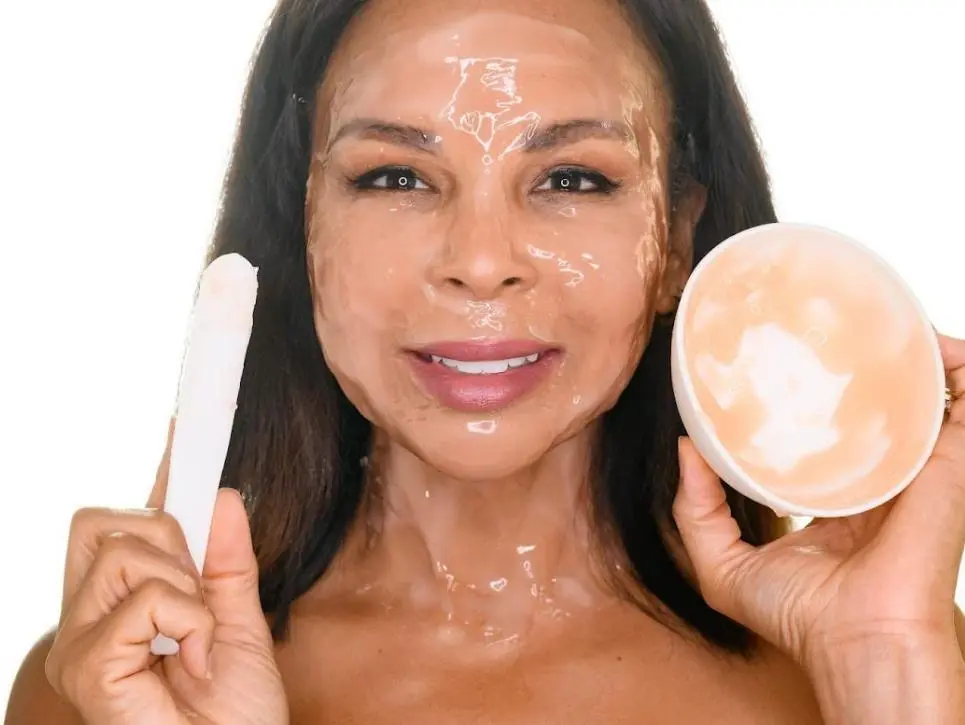 Woman holding Glo Derma skincare product and smiling